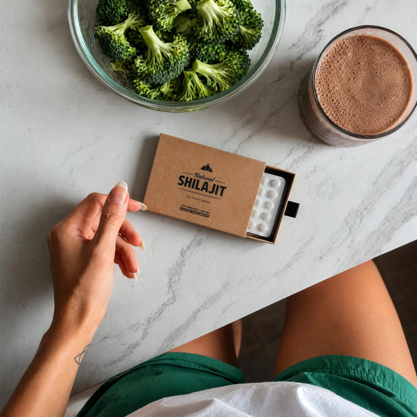 Woman with a box of shilajit tablets at a kitchen counter
